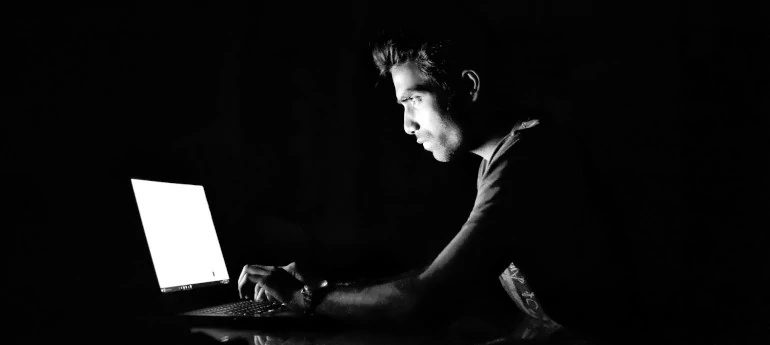 'Bild eines Hackers vor dem Laptop auf schwarzem Hintergrund'